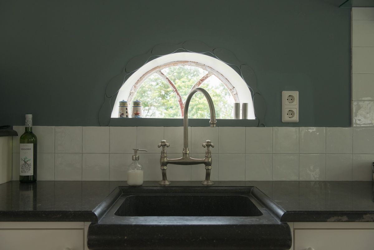 Cocina con fregadero rústico negro, grifo vintage y ventana en arco – Zeeuwshuisje casa de vacaciones, Koudekerke