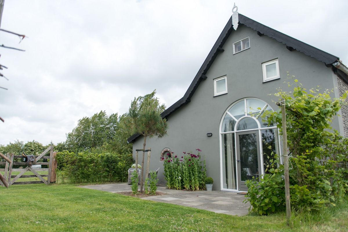 Exterior del granero reformado con ventana en arco y terraza – Zeeuwshuisje casa de vacaciones, Koudekerke
