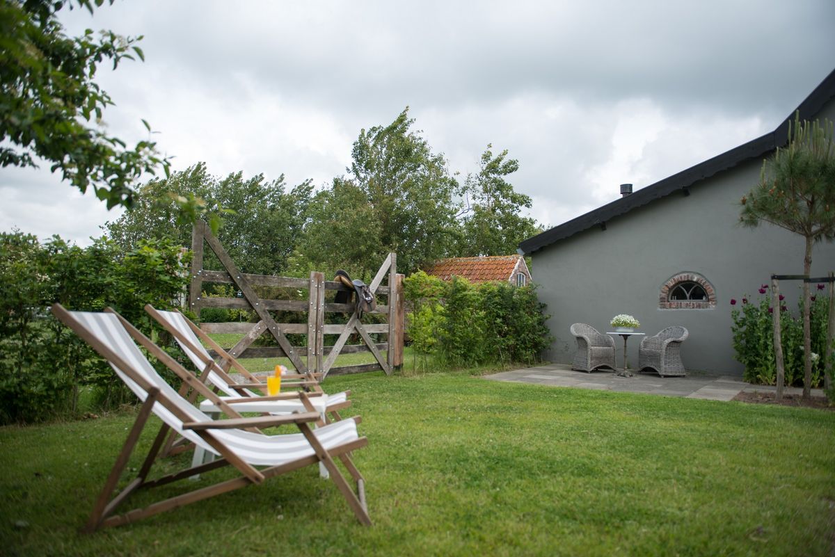 Jardín soleado con tumbonas y césped – Zeeuwshuisje casa de vacaciones, Koudekerke