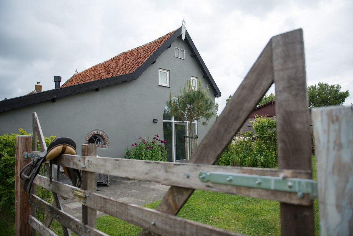 Exterior del granero reformado visto a través de una cancela de madera rústica – Zeeuwshuisje casa de vacaciones, Koudekerke