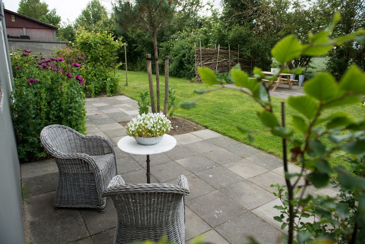 Terraza privada con sillas de mimbre y jardín frondoso – Zeeuwshuisje casa de vacaciones, Koudekerke